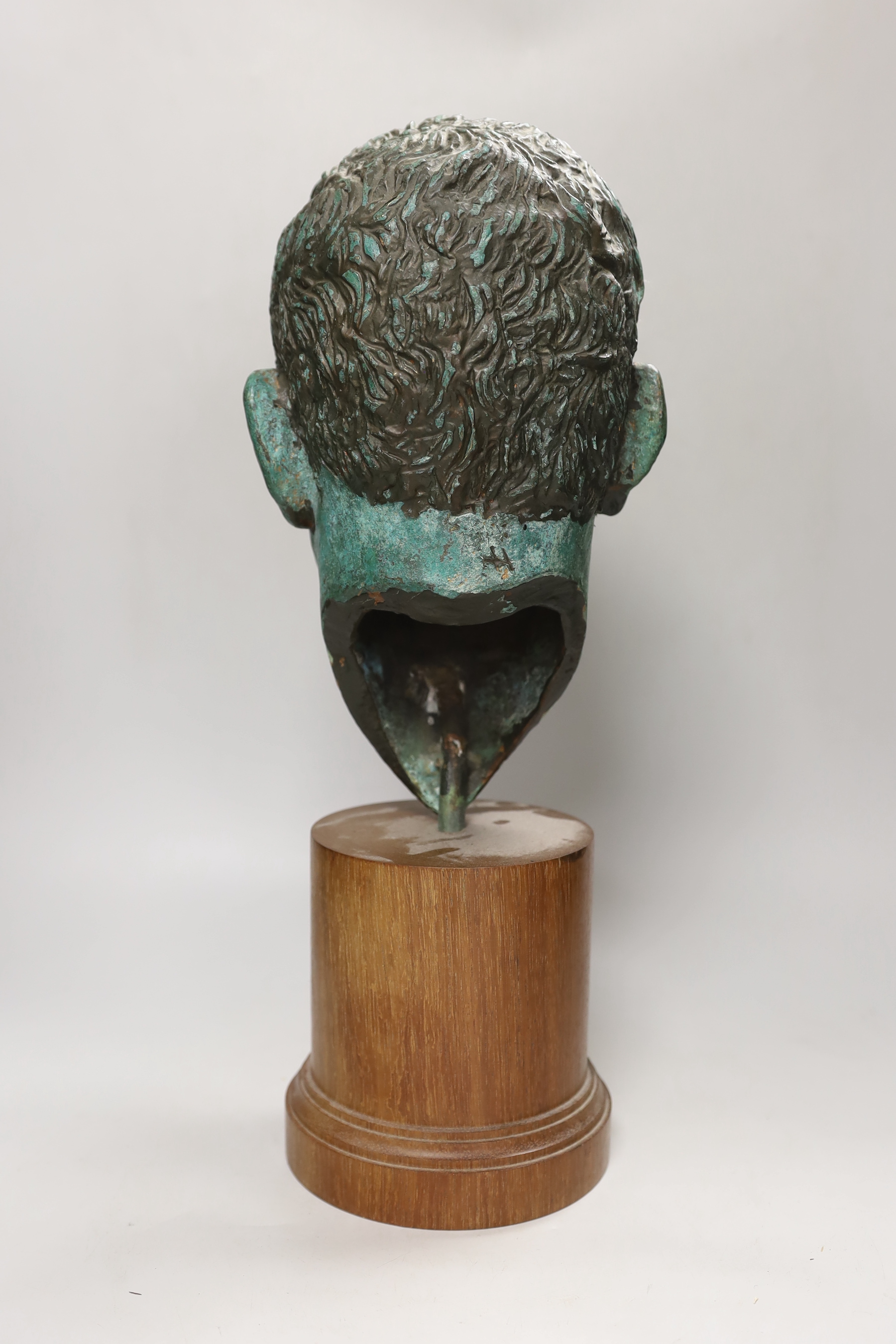 A verdigris metal head of a gentleman mounted on a wooden stand, 48cm high